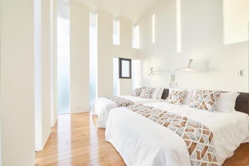 本部RIZOZAIZEN MOTOBU B的配有白色墙壁和木地板的客房内的两张床