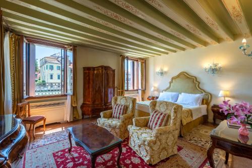 威尼斯Ca' dei Cuori on the Grand Canal的一间卧室配有一张床、两把椅子和一张桌子