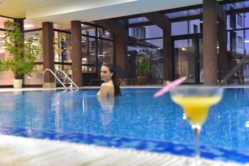 班斯科Royal Bansko - Half Board Plus & All Inclusive - Hot Pool & Jacuzzis的游泳池里的女人喝一杯