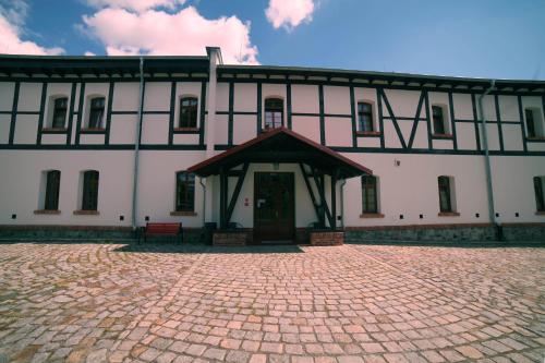 皮拉Noclegi Stara Wozownia的一座白色的大建筑,前面有红色的长凳