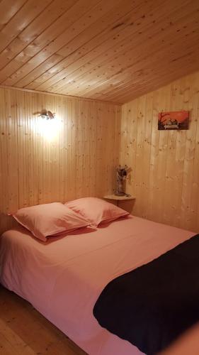 阿诺奈Chalet des Mésanges的一间带一张大床的卧室,位于带木墙的房间
