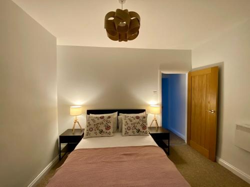 巴恩斯利Pillow Properties - Barnsley Centre的一间卧室配有一张带2个床头柜和2盏灯的床。