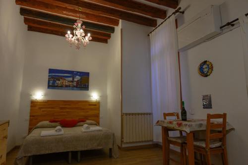 威尼斯Ca' del Megio的一间卧室配有一张床、一张桌子和一个吊灯。