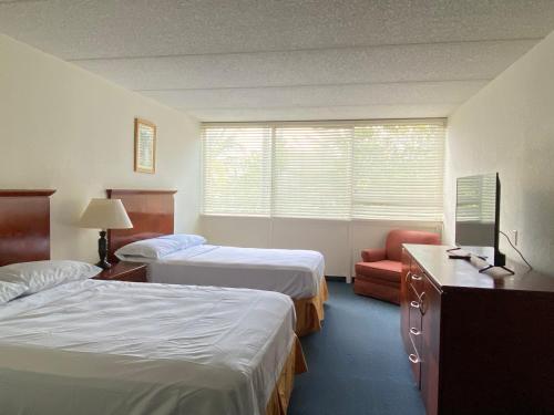 迈阿密Miami Gardens Inn & Suites的酒店客房,配有两张床和椅子