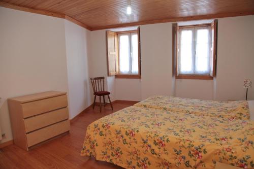 曼泰加什Casa das Tias的一间卧室配有一张床、一个梳妆台和两个窗户。