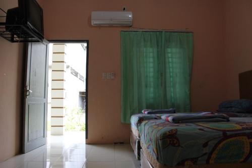 TanjungmorawaPenginapan Transit Tomato的一间卧室设有两张床和绿帘