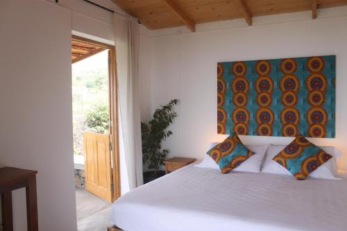圣菲利佩La Fora Ecolodge的卧室配有一张白色床,墙上挂有绘画作品