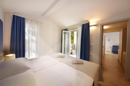 安卡兰Olive Family Suites - Hotel & Resort Adria Ankaran的卧室配有一张带蓝色窗帘的大型白色床