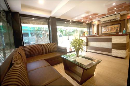 西里古里Apples Balaji Inn的带沙发和咖啡桌的客厅