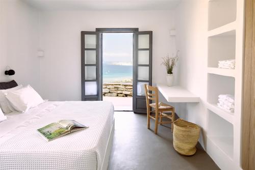 KolympithresAcron Villas Paros的卧室配有1张床、1张桌子和1把椅子