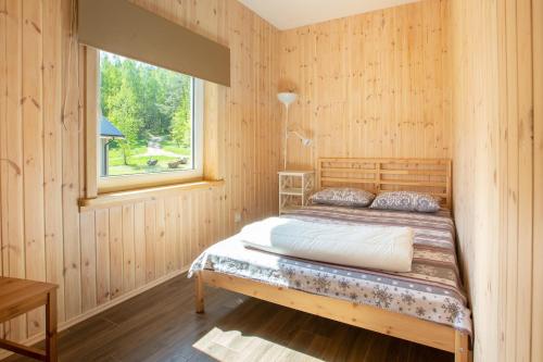 莫雷泰Ažuluokesos sodyba的木制客房的一张床位,设有窗户