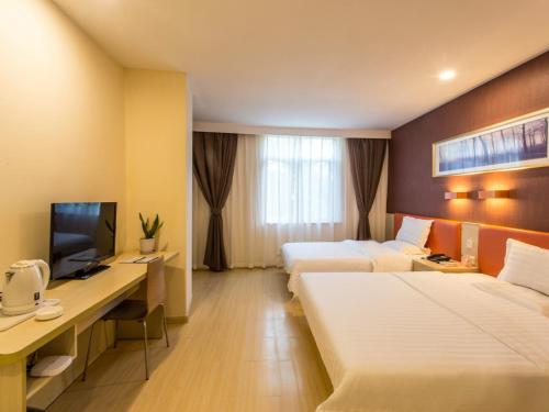苏州7天酒店·苏州狮山龙湖天街店的酒店客房配有两张床和一张书桌