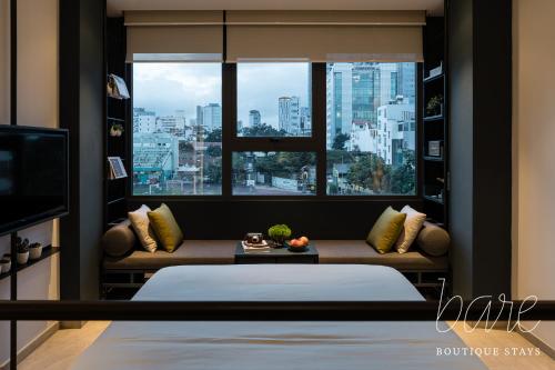 胡志明市Bare Chic - Bare Boutique Stays的一间卧室设有一张床和一个大窗户
