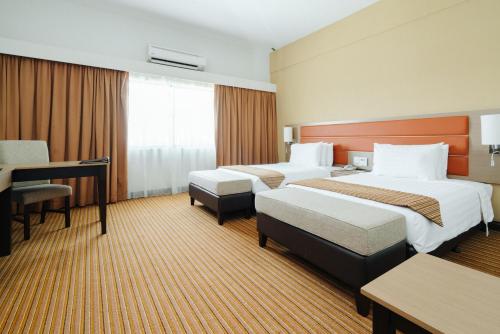 瓜拉丁加奴Raia Hotel & Convention Centre Terengganu的酒店客房配有两张床和一张书桌