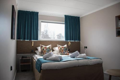 锡格蒂纳西格图拉霍登酒店与会议中心的一间卧室配有一张带蓝色窗帘的床和一扇窗户