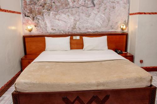 卢本巴希Park hôtel的一间卧室配有一张大床和木制床头板