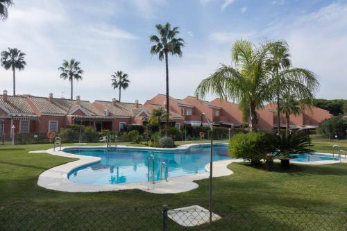奇克拉纳－德拉弗龙特拉Apartamento Pink Mariposas的棕榈树庭院内的游泳池