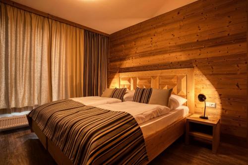 迪马诺卡多林纳DaSus Lux&Wellness Apartments Sosana的一间卧室设有一张带木墙的大床