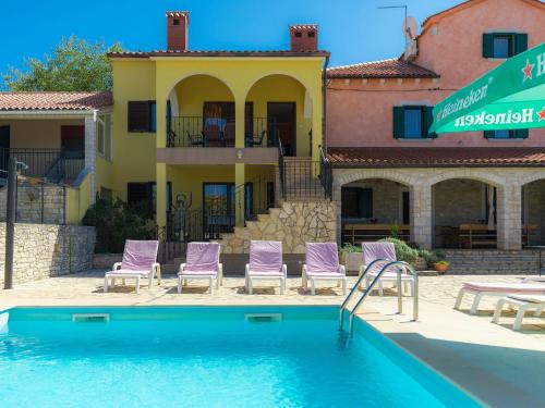 梅德詹Holiday Home Gracije - VOJ515 by Interhome的一个带紫色椅子的游泳池和一个房子