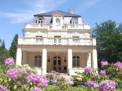 黑灵斯多夫Villa Bleichröder的带阳台和紫色鲜花的白色房子