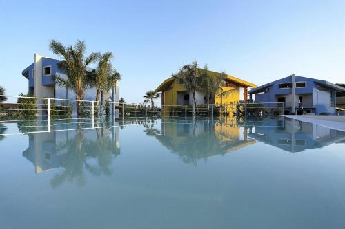 夏卡圣马可度假屋的一座拥有房屋和棕榈树的水池