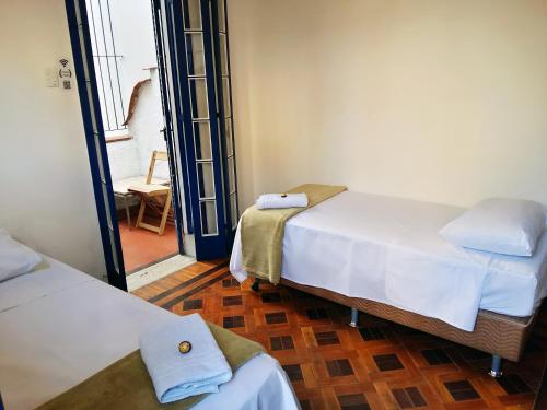 里约热内卢Farfalla Guest House的一间设有两张床的客房和一个带椅子的走廊