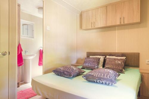 ZunaMobile Home 4p的一间卧室配有一张带紫色枕头的床