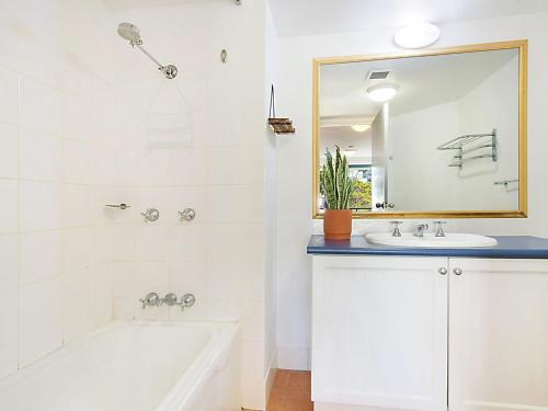 黄金海岸Calypso Plaza Resort Unit 215的带浴缸、水槽和镜子的浴室