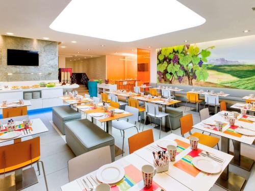马德里马德里普拉多宜必思尚品酒店的一间设有白色桌子和橙色椅子的餐厅