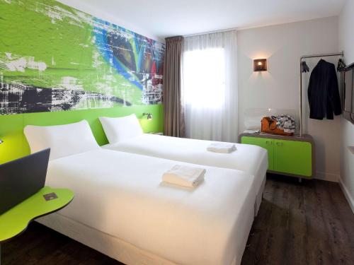 维勒班Ibis Styles Lyon Villeurbanne Parc de la Tête d'Or的酒店客房,设有白色的床和绿色的墙壁