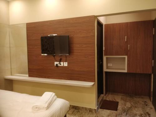 钦奈Icon Residency的一间设有床铺和墙上电视的房间