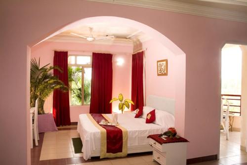 普里Toshali Sands Puri的一间设有床铺的卧室,位于一间设有红色窗帘的房间