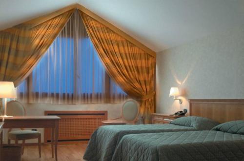 普雷甘纳·米拉内斯莫妮卡费奥拉酒店的一间卧室设有两张床、一张桌子和一个窗口。