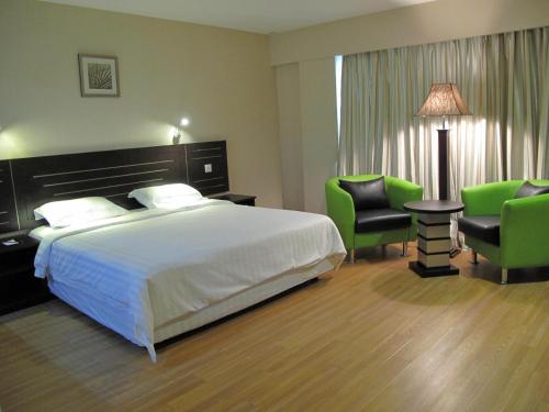 山打根拉卜酒店的酒店客房,配有一张床和两张绿色椅子