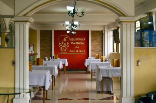 克萨尔特南戈Hotel y Restaurante Castillo de los Altos的一间设有白色桌子和红色墙壁的用餐室
