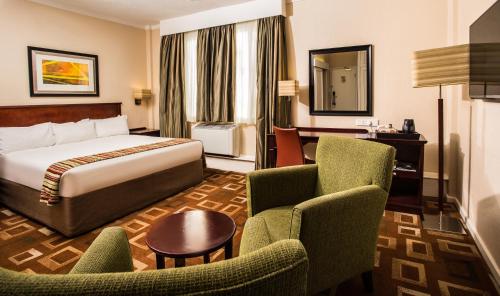 肯普顿帕克坦博国际机场庭院酒店的酒店客房,配有一张床和两把椅子