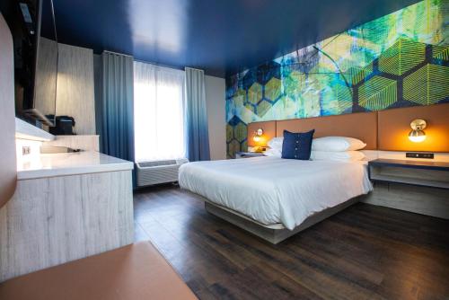 格林斯伯勒Hotel Denim的卧室配有一张床,墙上挂有绘画作品