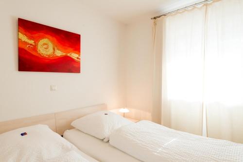 巴德艾比林Ferienwohnungen "Am Kurpark"的卧室配有一张白色床,墙上挂有绘画作品