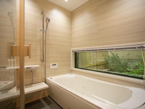 金泽金泽马奇诺奥托酒店的带浴缸的浴室和窗户。