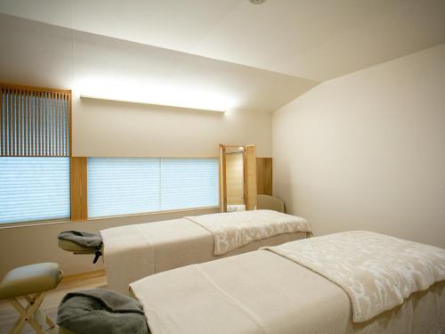 金泽金泽马奇诺奥托酒店的一间卧室设有两张床、一把椅子和一个窗户。