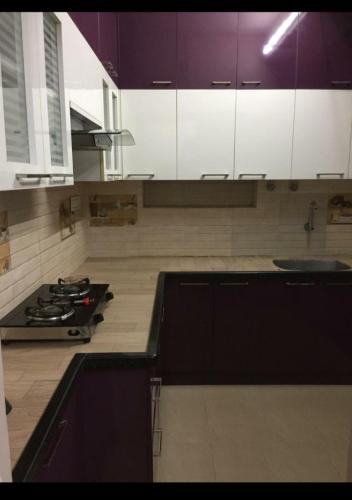 钦奈Avvairam Service Apartment - C9的厨房配有紫色和白色的橱柜和炉灶。
