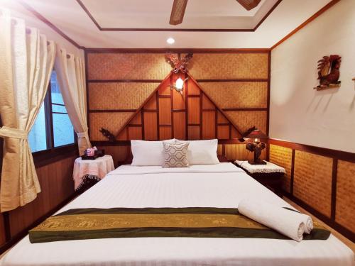 曼谷TAVEE Guesthouse的一间卧室配有一张大床和木制床头板