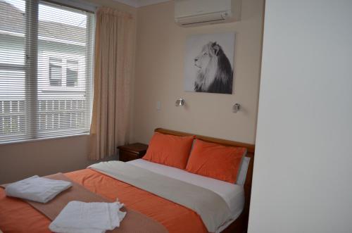 马斯特顿Villa 185- Central Masterton的一间卧室配有带橙色枕头的床和窗户。