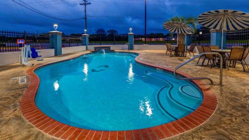 阿尔文SureStay Plus Hotel by Best Western Alvin的夜间游泳池配有桌椅