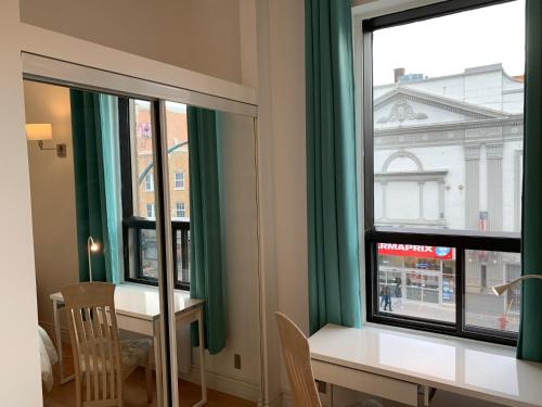 蒙特利尔Chambres EL MEDITERRANEO Rooms的客房设有桌子和2扇带绿色窗帘的窗户。