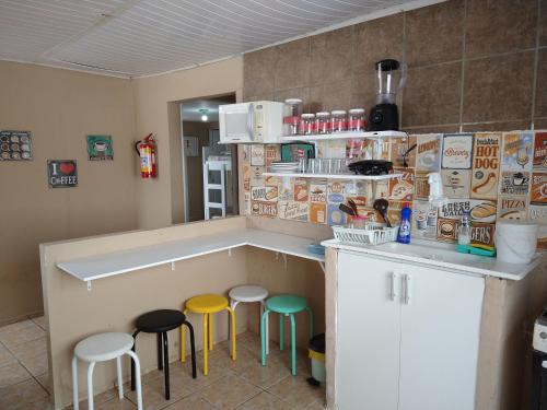 累西腓Casa Aeroporto Pousada的厨房在柜台前设有三把凳子