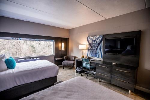 哈里斯堡Hotel Indigo Harrisburg – Hershey的酒店客房配有一张床、一张书桌和一台电视。