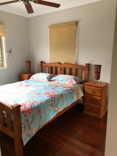 谭伯连山Tamborine Mountain Accommodation的一间卧室配有木床和床头柜