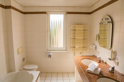 Löhnberg皇冠餐厅及酒店的一间带两个盥洗盆、浴缸和卫生间的浴室