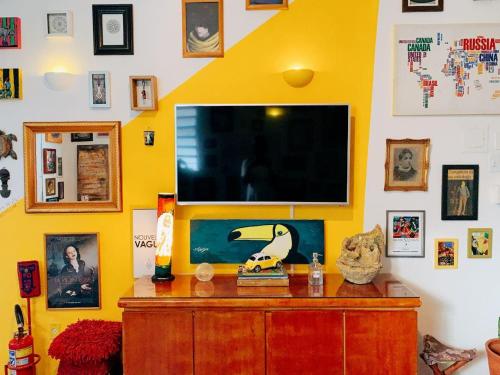 累西腓Zili Pernambuco - Hostel Pousada的一间起居室,在黄色的墙上配有电视